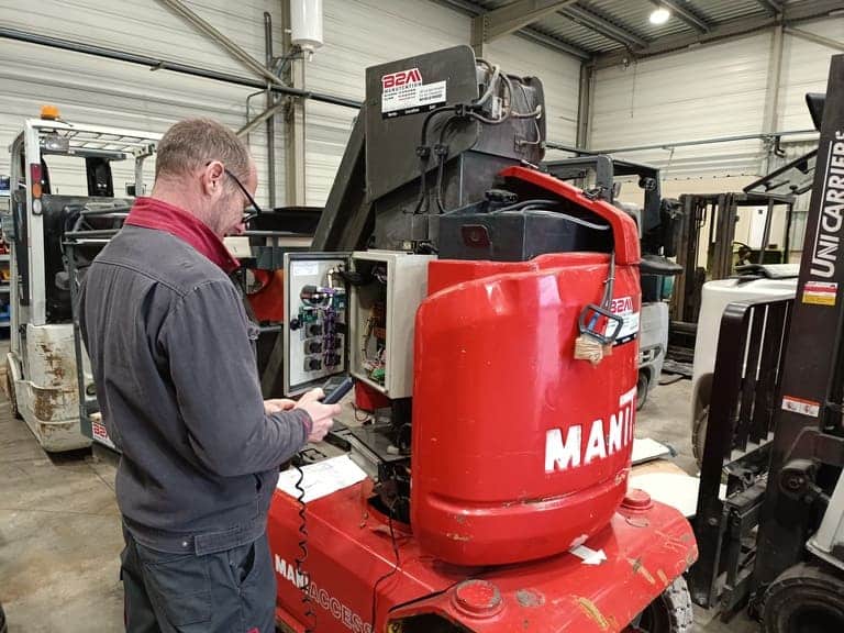 Image d'un technicien de maintenance qui effectue un audit sur une nacelle élévatrice Manitou