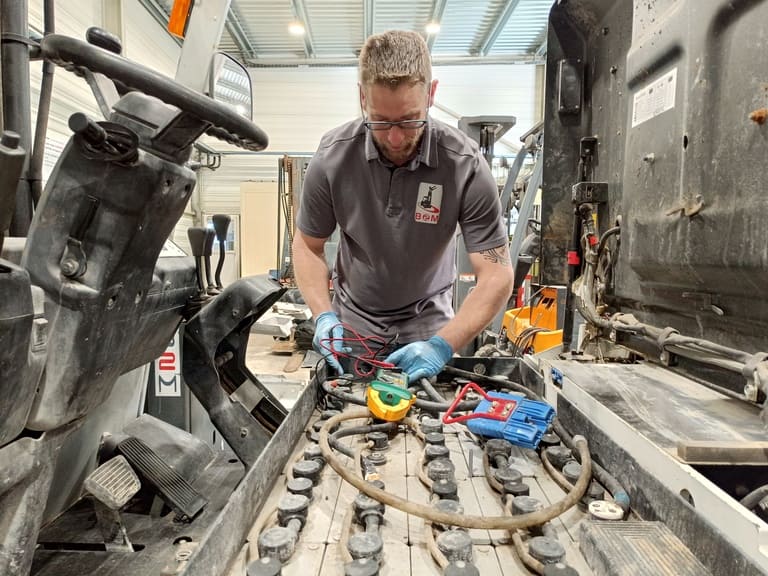 Image d'un technicien de maintenance en train de réaliser l'entretien et la régénération d'une batterie de chariot élévateur