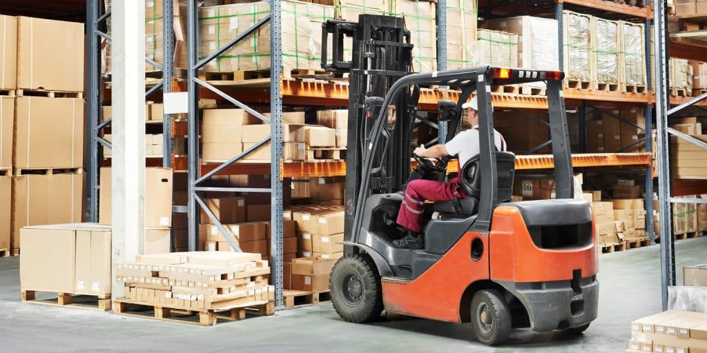 Un cariste conduit un chariot élévateur d'occasion dans un entrepôt de stockage