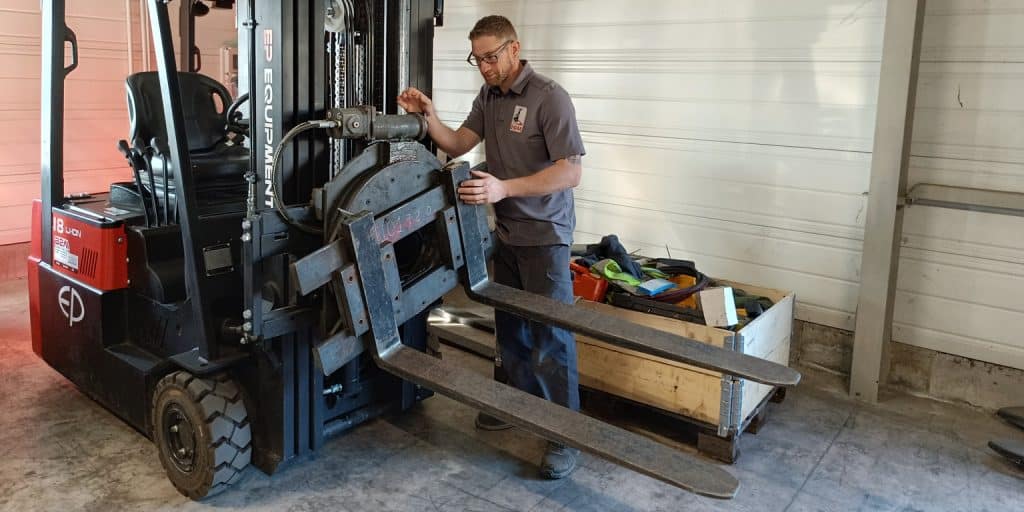 Image d'un technicien de maintenance en train de monter une tête rotative sur un chariot élévateur