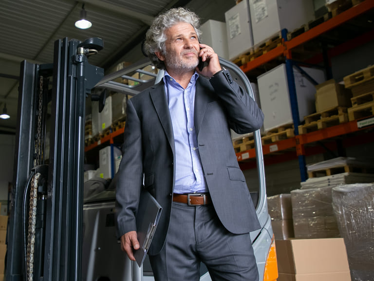 Image d'un homme au téléphone, devant un chariot élévateur