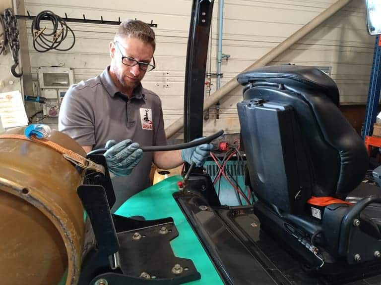 Image d'un technicien de maintenance en cours de remplacement d'un flexible hydraulique sur un chariot élévateur gaz Mitsubishi Forklift