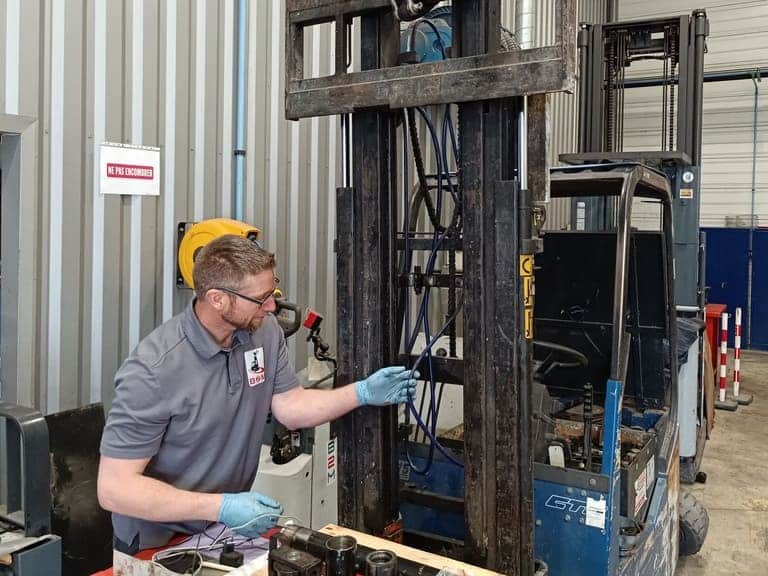 Image d'un technicien en train de remplacer un flexible hydraulique sur un chariot élévateur